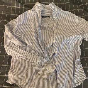 Skjorta  - Blåvit skjorta med ränder och knappar vid händer och från halsen ner 