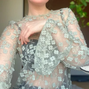 Grön blus - En olivgrön spetsblus med trumpetärmar och knäppning i nacken. Den är aldrig använd, så den är i mycket gott skick!