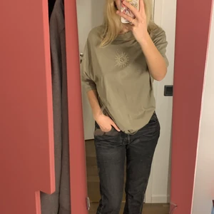 Millitärgrön T-shirt  -  Militärgrön åh versus t-shirt med en tryckt sol på bröstet . Använd 1 gång. Nypris 250