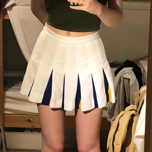 vit blå och gul tenniskjol i size S/XS - supersöt vit tenniskjol med blå och gula detaljer. köpt second hand för några år sen och är i fint skick! använd ca 5 gånger. 