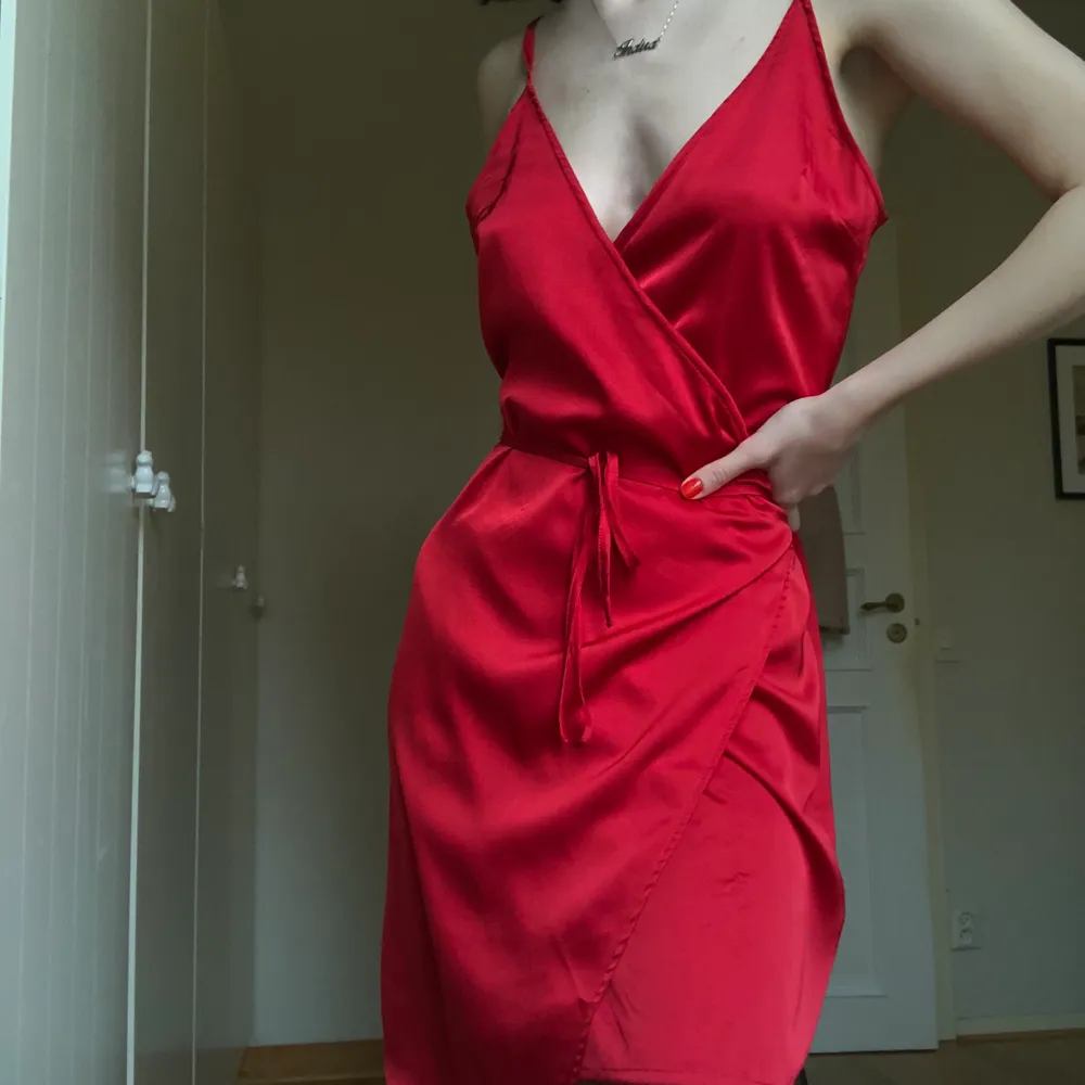 En klänning i wrap stil med band att knyta i midjan. Justerbara axelband. Röd satin tyg. Knappt använd. Storlek 36. Frakt 62 kr eller kan mötas i Malmö #nakd #klänning #röd #satin. Klänningar.