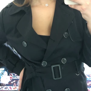 Svart kappa strl 38 - En helt oanvänd svart kappa med band från primark i strl 38. Den går ungefär till mitten av låren på mig som är 165cm. Möts antingen upp i centrala Stockholm eller så skickar jag ett spårbart paket med postnord där köparen står för frakten. 