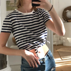 Randig croppad t-shirt - Blå och vit randig croppad t-shirt med knytning fram. 