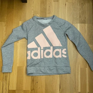 Grå tröja, Storlek XS - En grå sweatshirt med rosa adidastext. Använd 1 gång för ca 1 år sen. Skön att ha på sig när man chillar osv. 