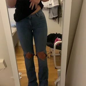 Blåa bootcut jeans med hål - Använda 1 gång, egna hål och slits längst ned. Sköna, säljer för kommer ej till användning 