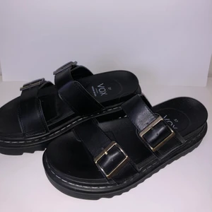 Vox svarta slip in sandaler - Säljer mina svarta slip in sandaler, använda fåtal gånger men använder inte längre. 4 cm platå och skysterbara spännen över foten. Storlek 37! Skriv för frågor