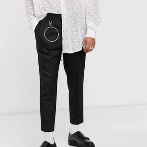 Svarta kostymbyxor - Asos Design - Jättefina svarta kostymbyxor i jaquardmönstrat tyg från Asos! I storlek W28 L30. Välanvända och i bra skick, lite noppriga på vissa ställen :) Silverringen på bild 1 och 3 följer inte med. Nypris 548, säljer för 100!