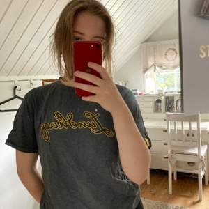 En grå t-shirt från Lundhags med gul text       I storlek S