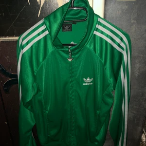 Grön Adidaskofta  - En grön adidaskofta i storlek S. Fint skick, inga defekter. Hänger bara i garderoben och används ej. Skriv vid intresse! Kan användas som träningströja eller som en vanlig kofta! Frakt ingår! 
