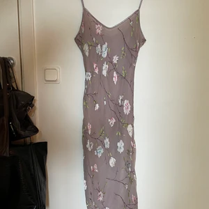 . - Grå klänning med blommor, figursydd 