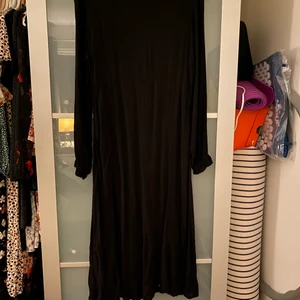 Klänning - Svart klänning med blixtlås i rygg, samt gummibandsresår vid armslut.