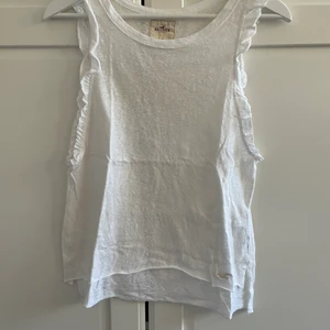 Hollister vitt linne med volangärm  - Hollister vitt linne med volangärm, XS. 