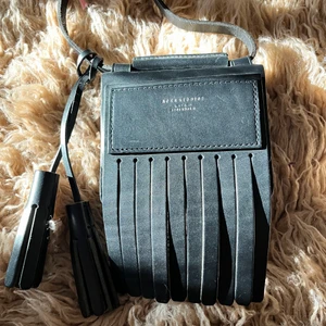 Acne studios liten läderväska OANVÄND - Magisk väska från Acne Studios i svart skinn med två svarta tofsar. i toppenskick! Stängs med en magnet och rymmer det nödvändigaste. En liten innerficka finns.  Mått på väskan (utan fransarna) 15x12 cm 