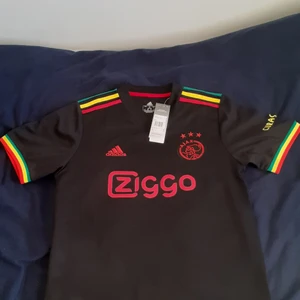 Ajax jersey  - Hej, säljer ajax 21-22 tredje jersey som blev bannad av UEFA från champions league.Det är samarbete med Bob Marleys familj. Jersey är helt ny.