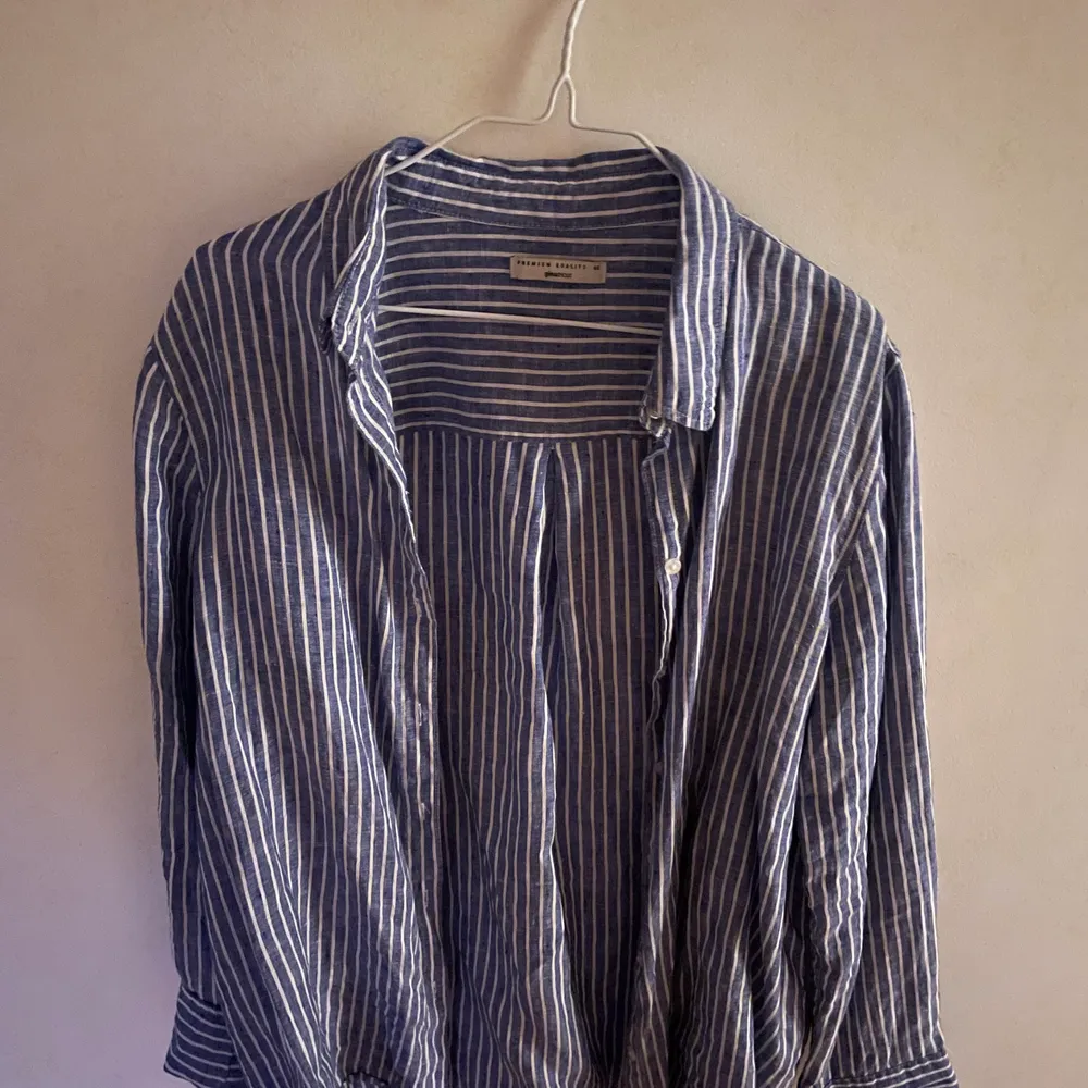Det är en blårandig linneskjorta från Gina tricot i storlek 40. Den är lite stelare i materialet eftersom det är linne. Men den är ändå rätt stor, sann till storleken . Skjortor.