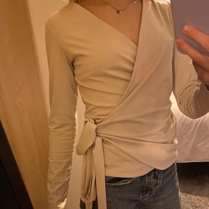 Topp med knytning - Säljer en ljusbeige topp med knytning från hm i storlek xs. Fint skick men kommer tyvärr inte till användning💗