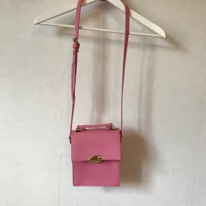 Rosa väska, NA-KD - Rosa väska från NA-KD i en härligt pigg rosa! Två fack inuti och helt nyskick. Justerbart band.  Kan mötas i Stockholm eller skicka mot fraktkostnad! ✨🌸✨