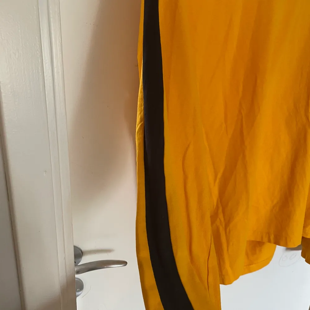 Långärmad gul tröja med svarta ränder på sidorna av armarna. Knappt använd. Tröjor & Koftor.