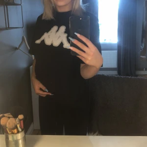 En svart t-shirt från märket kappa  - En helt vanlig svarat t-shirt med vitt kappa märke                   Lite lång i längden 