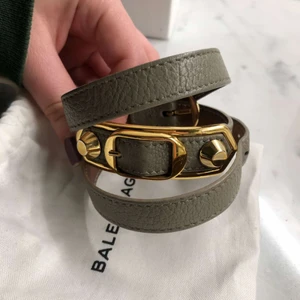 Balenciaga armband  - Säljer ett så fint grått balenciaga armband med guld detaljer! Går att spänna så passar alla storlekar. Knappt använt så i nyskick, säljer då det inte kommer till användning.💕 Box, dustbag och äktetsbevis medföljer!