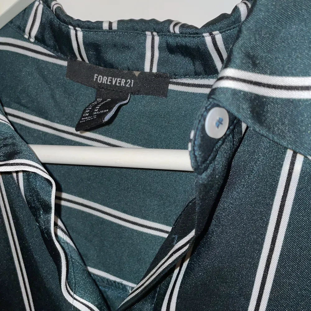 En grön randig silkes skjorta från Forever 21. Använd endast en gång. Det bästa med skjortor är att man kan styla dem hur man vill!! Köparen står för frakten.. Skjortor.