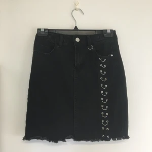 Kjol  - Svart kjol med slitna detaljer och metallringar. 