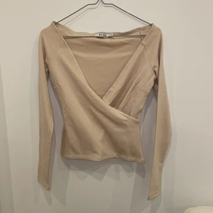 Beige top från NAKD - Säljer denna fina top från NAKD då jag aldrig använt den. Sitter hur bra som helst, men ganska urringad. Storlek XS men passar S också. 