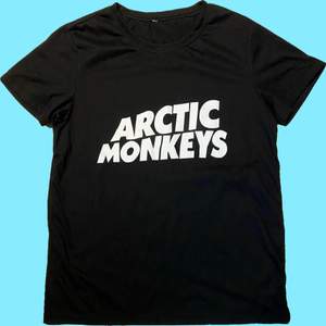 En svart T-shirt med Arctic Monkeys tryck. Tyg av polyester 