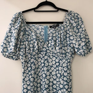 Blommig klänning från Missguided  - Jättefin klänning från Missguided. Klänningen är aldrig använd. Klänningen är i siden imiterat tyg, sitter jätte fint. Den har en dragkedja i ryggen, slits över vänster ben, gummiband längst ut i ärmarna och detaljer vid brösten. Köparen står för frakten