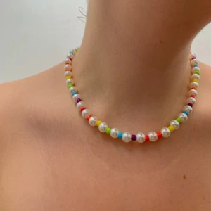 Pärlat halsband med färgade pärlor. - Underbart fint halsband i kort modell. Tas av och på med en klo där bak och har elastisk tråd. 