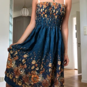 Klänning - Så himla fin sommarklänning köpt second hand!! Smockad på överdelen. Blommönster i rostfärgad/gul, lite grönt osv på toppen och nedre delen av kjolen. Färgerna visas bra på bilderna. Är en 34-36 i vanliga fall men skulle defentift passa större storlekar!  Älskar den här klänningen men använder den för sällan!!
