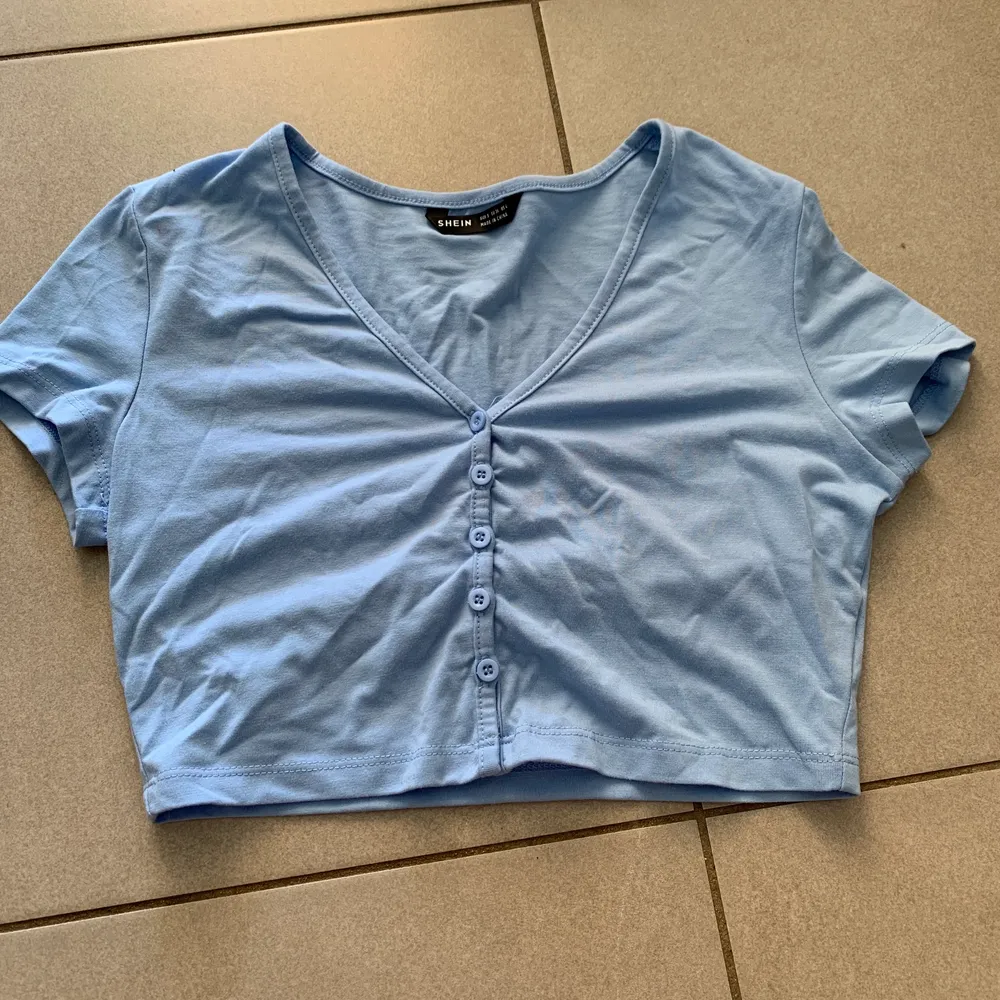 En blå T-shirt med knappar från SHEIN i storlek s. T-shirts.