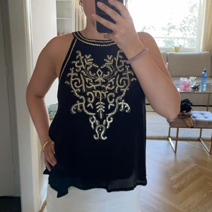 Topp  - Svart topp med guldiga paljett detaljer. Köp i Spanien, aldrig använd!