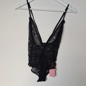 Spetsbody från hunkemöller - Spetsboddy från hunkemöller. Oanvänd storlek S. Guld spännen annars helt svart. Tre knappar längt ner för att öppna och stänga. Får med en pressentlåda från hunkemöller