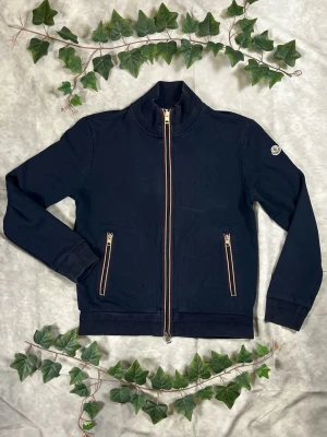 Moncler Maglia Cardigan Zip – Navy – Strl S - |Färg: Navy/mörkblå, trikolor-detaljer | Modell: Maglia Cardigan Zip | Storlek: S, normal passform | Skick: Grade B+, 8,5/10 (mindre hål) | Hör av dig ifall du har funderingar!