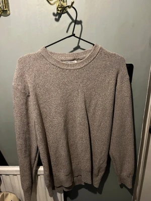 Beige stickad tröja med rund hals från Zara - En stilren beige stickad tröja från Zara med rund halsringning och långa ärmar. Tröjan har ribbstickade muddar vid ärmslut och nederkant, vilket ger en klassisk och enkel look. 