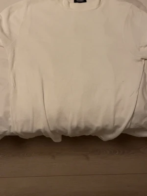 Vit t-shirt från Pull&Bear - En klassisk vit t-shirt från Pull&Bear med rund halsringning. Enkel och stilren design utan tryck eller mönster, perfekt att matcha med allt. Tillverkad i mjuk bomull för en skön känsla hela dagen.