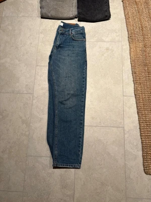 Blå jeans från Grunt med rak passform - Ett par mindre slitnaingar gjorda runt om på jeansen. Säljer ett par klassiska blå jeans från Grunt med rak passform och normal midja. Jeansen har fem fickor, knappgylf och är tillverkade i slitstark bomullsdenim. Perfekta för en avslappnad och stilren look.