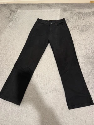 Svarta bootcut jeans - Snygga svarta jeans med bootcut passform och klassisk femficksdesign. Jeansen har bälteshällor och knappgylf. Perfekta för dig som gillar en tidlös och clean look.