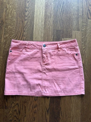 Korall jeanskjol från ONLY - Snygg rosa kort jeanskjol från ONLY med klassisk femficksdesign, bälteshällor och knappstängning fram. Kjolen har en rak passform och är tillverkad i mjuk bomull med lite stretch för extra komfort. Kameran kunde inte fånga upp färgen så bra men på bild 3 ser ni den bättre. Skriv för fler bilder!