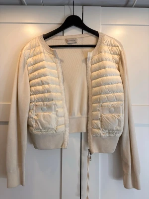 Moncler cardigan  - Vit cardigan från Moncler i storlek xs men passar även s. Väldigt fint skick inga tydliga tecken på slitage. Har tyvärr inte kvitto utan bara qr-koden i jackan som äkthetsbevis då jag köpte den på Plick. Skriv för fler bilder eller frågor💕