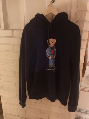 Polo Bear Ralph Lauren Hoodie  - Blå hoodie från Ralph Lauren med klassiskt björn motiv storlek L sitter och bra samt i bra skicka hör gärna av dig om du har några frågor eller funderingar eller om du vill diskutera pris