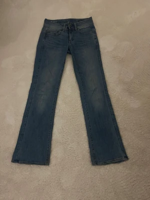 Blå bootcut jeans från G star - Snygga blå jeans med bootcut passform och klassisk femficksdesign. Jeansen har en låg midja och är tillverkade i ett mjukt denimtyg som ger en avslappnad look. Perfekta för dig som gillar en tidlös stil med lite utsvängda ben. Säljer dessa svin snygga jeans som är försmå! 