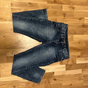 Blå jeans från Lab Industries - Säljer ett par snygga jeans från Lab Industries i tvättad blå denim. Klassisk femficksmodell med knapp och dragkedja framtill. Jeansen har en rak passform och är perfekta för en chill stil. Materialet är bomull och färgen är mörkblå med slitningar.