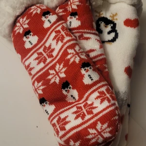 Helt nya barnstrumpor 28-30  - Mysiga vinterstrumpor från Carbotex med fluffigt foder. Ena paret är rött med vita snögubbar och snöflingor, andra paret är vitt med svarta pingviner och röda hjärtan. Perfekta för kalla dagar och har en riktigt vintrig vibe.