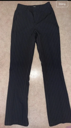 Svarta randiga kostymbyxor BikBok - Snygga svarta kostymbyxor från BikBok i storlek 34 med vita tunna ränder. Byxorna har utsvängda ben passform och klassisk midja, perfekta för en stilren look.