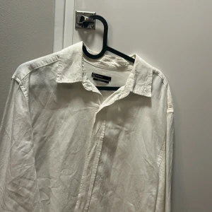 Vit linneskjorta - Klassisk vit skjorta i storlek m. Skjortan har lång ärm, krage och knappar framtill. Perfekt för dig som gillar enkel och stilren design. Materialet är mjukt och känns skönt mot huden.