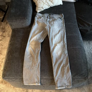 Replay ljusgrå jeans straight fit - Snygga ljusgrå jeans från Replay med klassisk femficksdesign och raka ben. Jeansen har en stilren look med Replay-logga på bakfickan och patch i midjan. Perfekt för dig som gillar en clean och enkel stil. Materialet är mjukt jeans och passformen är normal.