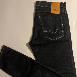 Replay Hyperflex Anbass jeans, svart - Säljer ett par svarta Replay Hyperflex Anbass jeans i slim fit. Klassisk femficksmodell med snygga kontrastsömmar och läderpatch bak. Stretchigt material som sitter skönt och följer kroppen. Perfekt för dig som gillar stilrena och moderna jeans.