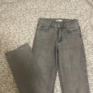 Grå jeansbyxor från Gina Tricot - Snygga grå jeansbyxor från Gina Tricot i klassisk femficksmodell. Byxorna är utsvängda, normal passform och mid waist. Jeansen är tillverkade i bomull och har en fransad kant vid benslut för en cool touch.